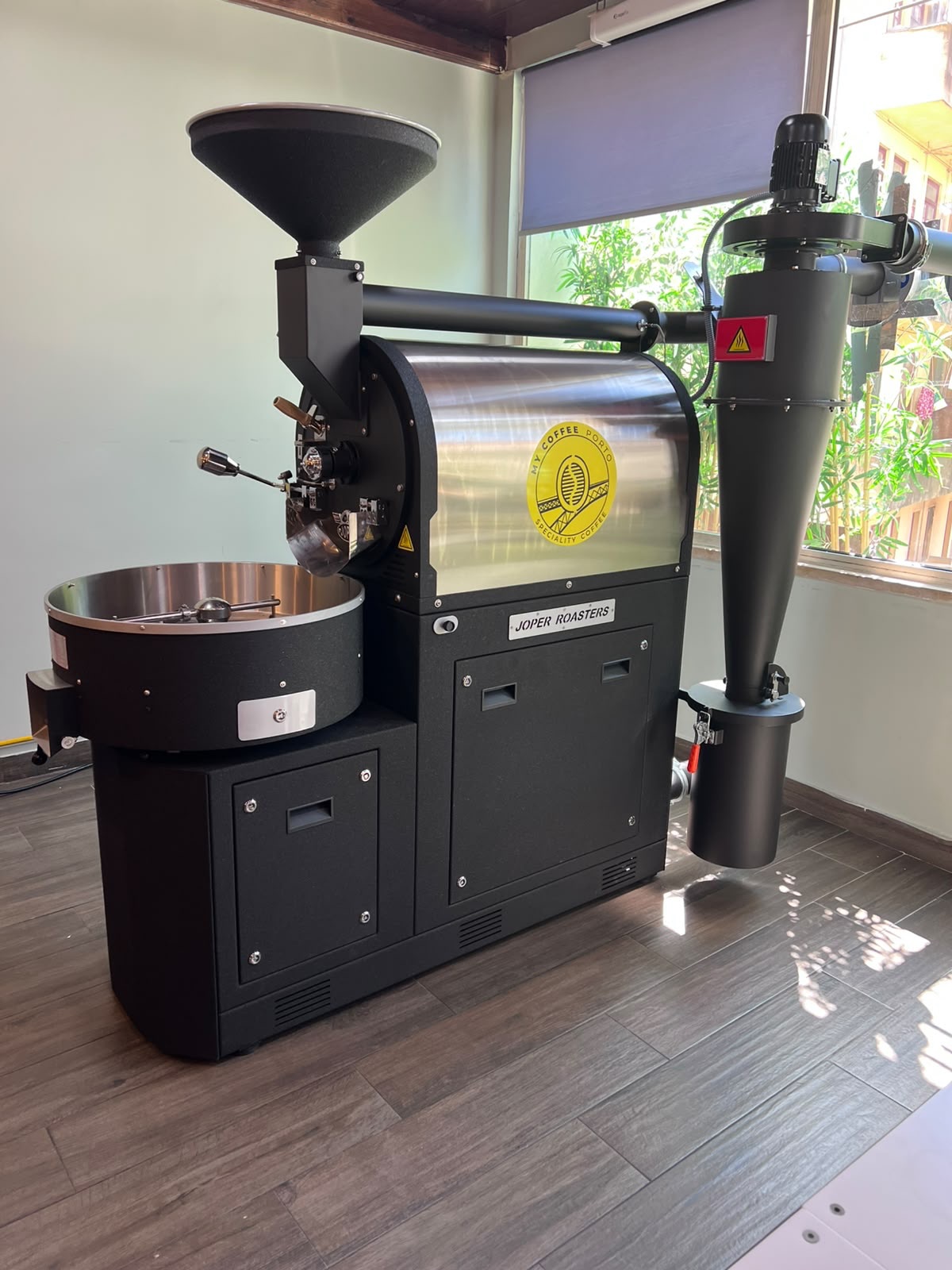 The My Coffee Porto Joper drum roaster with the brand emblem, at our roastery in Porto
